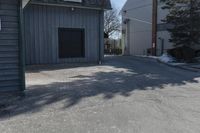 a man skates down the street in front of a building with a garage and an outdoor grill area