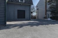 a man skates down the street in front of a building with a garage and an outdoor grill area