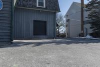 a man skates down the street in front of a building with a garage and an outdoor grill area