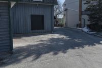 a man skates down the street in front of a building with a garage and an outdoor grill area