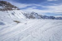 a man skiing down a snowy mountain path, with the sun behind him and clouds overhead