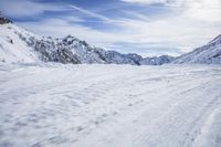 a man skiing down a snowy mountain path, with the sun behind him and clouds overhead