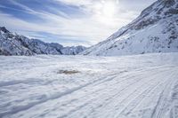 a man skiing down a snowy mountain path, with the sun behind him and clouds overhead