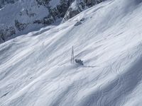 a man riding down the side of a snow covered hillside on skis while holding on to a pole