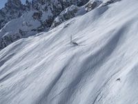 a man riding down the side of a snow covered hillside on skis while holding on to a pole