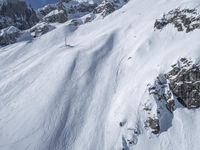 a man riding down the side of a snow covered hillside on skis while holding on to a pole