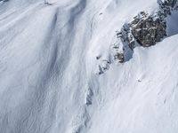 a man riding down the side of a snow covered hillside on skis while holding on to a pole