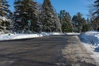 a man skiing down a road on a bright sunny day in a park area with snow