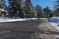 a man skiing down a road on a bright sunny day in a park area with snow