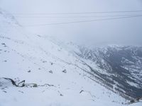 man riding a snowboard down a snow covered slope next to power lines and wires