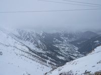 man riding a snowboard down a snow covered slope next to power lines and wires