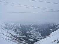 man riding a snowboard down a snow covered slope next to power lines and wires