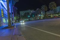 a man stands on a city street with palm trees on both sides of the road