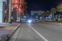 a man stands on a city street with palm trees on both sides of the road