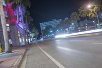 a man stands on a city street with palm trees on both sides of the road