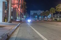 a man stands on a city street with palm trees on both sides of the road