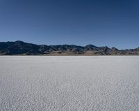 a man is standing in the desert with a remote control kite behind him that looks like he's in the middle of the frame