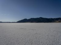 a man is standing in the desert with a remote control kite behind him that looks like he's in the middle of the frame