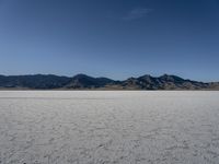 a man is standing in the desert with a remote control kite behind him that looks like he's in the middle of the frame