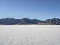 a man is standing in the desert with a remote control kite behind him that looks like he's in the middle of the frame