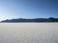 a man is standing in the desert with a remote control kite behind him that looks like he's in the middle of the frame