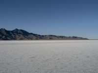 a man is standing in the desert with a remote control kite behind him that looks like he's in the middle of the frame