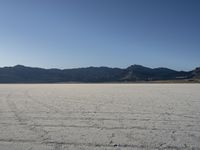 a man is standing in the desert with a remote control kite behind him that looks like he's in the middle of the frame