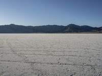 a man is standing in the desert with a remote control kite behind him that looks like he's in the middle of the frame