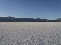 a man is standing in the desert with a remote control kite behind him that looks like he's in the middle of the frame