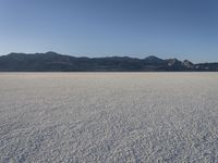 a man is standing in the desert with a remote control kite behind him that looks like he's in the middle of the frame