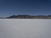 a man is standing in the desert with a remote control kite behind him that looks like he's in the middle of the frame