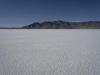 a man is standing in the desert with a remote control kite behind him that looks like he's in the middle of the frame