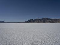 a man is standing in the desert with a remote control kite behind him that looks like he's in the middle of the frame