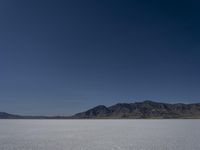 a man is standing in the desert with a remote control kite behind him that looks like he's in the middle of the frame