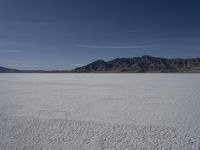 a man is standing in the desert with a remote control kite behind him that looks like he's in the middle of the frame