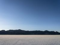 a man is standing in the desert with a remote control kite behind him that looks like he's in the middle of the frame