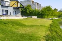 a man standing in a yard with an umbrella on top of a green field next to a building