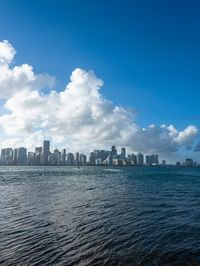 a man is standing on a beach in the ocean and looking down at a skyline