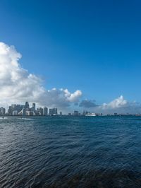 a man is standing on a beach in the ocean and looking down at a skyline