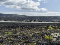 a man stands on a road in the mountains above some barren land and there is only a hill in the distance