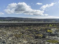 a man stands on a road in the mountains above some barren land and there is only a hill in the distance