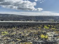 a man stands on a road in the mountains above some barren land and there is only a hill in the distance