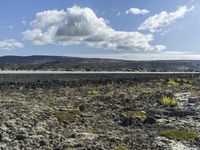 a man stands on a road in the mountains above some barren land and there is only a hill in the distance