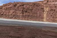 man standing on the side of the road next to rocks with a motorcycle on the side