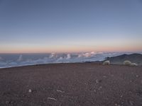 a lone man standing at the top of a hill and looking at the clouds below him