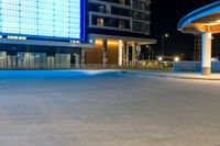 a man wearing sunglasses walking down the street at night with a skateboard in front