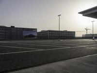 the man is taking a photo in an empty parking lot outside of a building at sunset