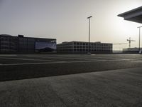 the man is taking a photo in an empty parking lot outside of a building at sunset