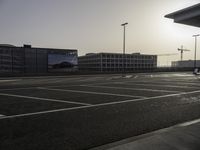 the man is taking a photo in an empty parking lot outside of a building at sunset