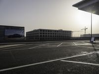 the man is taking a photo in an empty parking lot outside of a building at sunset